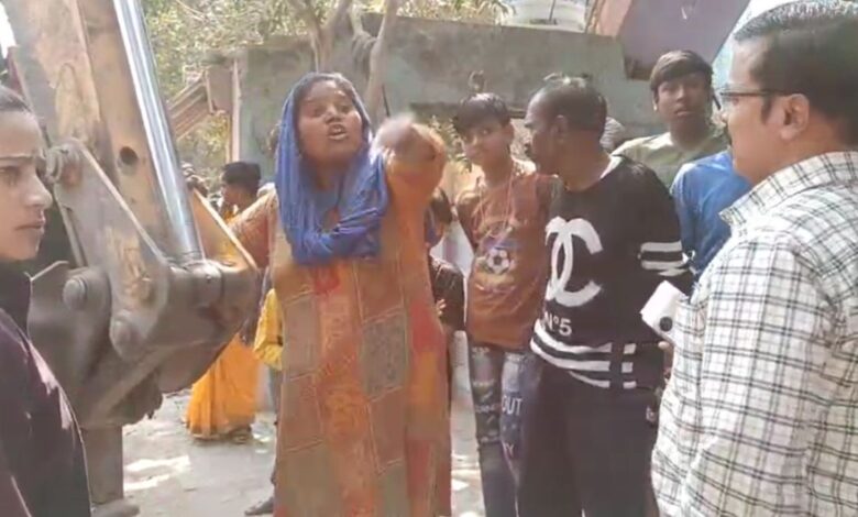 जेसीबी के सामने खड़ी महिला, रविंद्र नगर गेट पर अतिक्रमण हटाने पर विवाद
